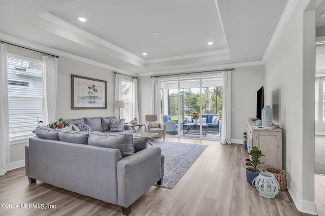 living room featuring crown molding, a tray ceiling, and light hardwood / wood-style flooring