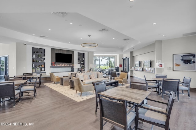 dining area with a tray ceiling, built in features, and light hardwood / wood-style flooring