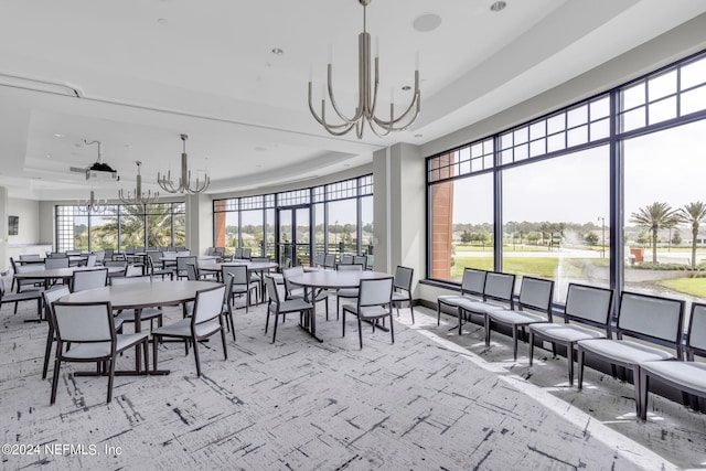 sunroom / solarium featuring a tray ceiling and a chandelier