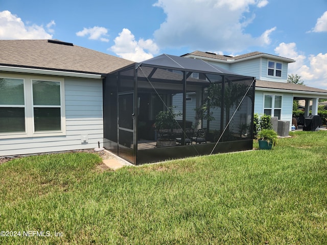 back of house featuring a lanai, central AC, and a lawn