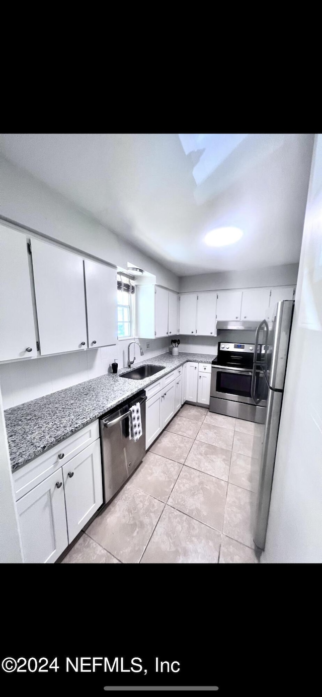 kitchen featuring light stone counters, under cabinet range hood, a sink, white cabinets, and appliances with stainless steel finishes