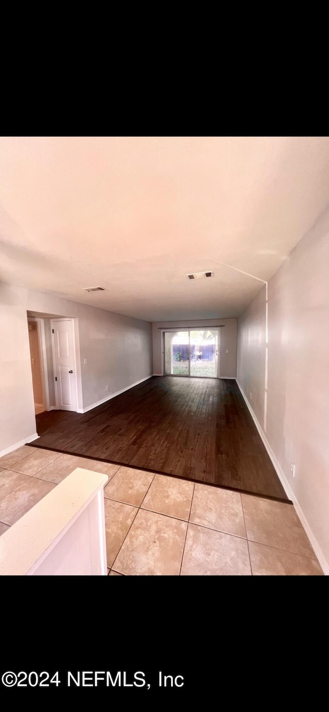 hallway featuring tile patterned flooring, visible vents, and baseboards