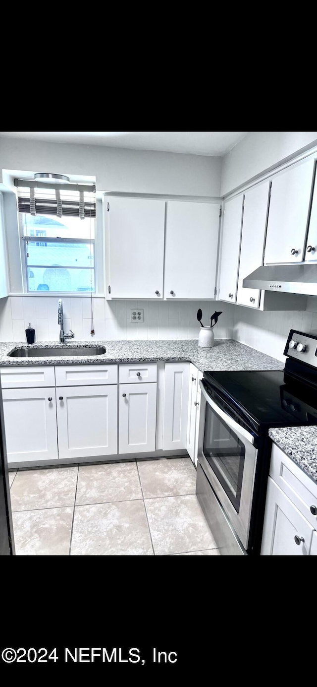 kitchen featuring electric range, light stone countertops, under cabinet range hood, white cabinetry, and a sink