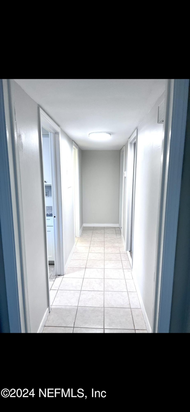 hall featuring baseboards and light tile patterned floors