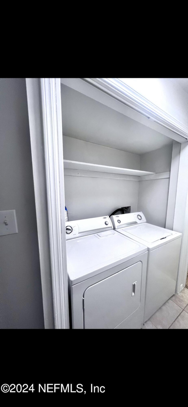laundry room featuring laundry area, light tile patterned flooring, and washing machine and clothes dryer