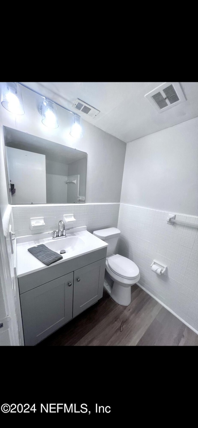 bathroom with vanity, visible vents, tile walls, and wainscoting