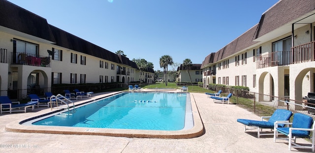 community pool with a residential view, a patio, and fence