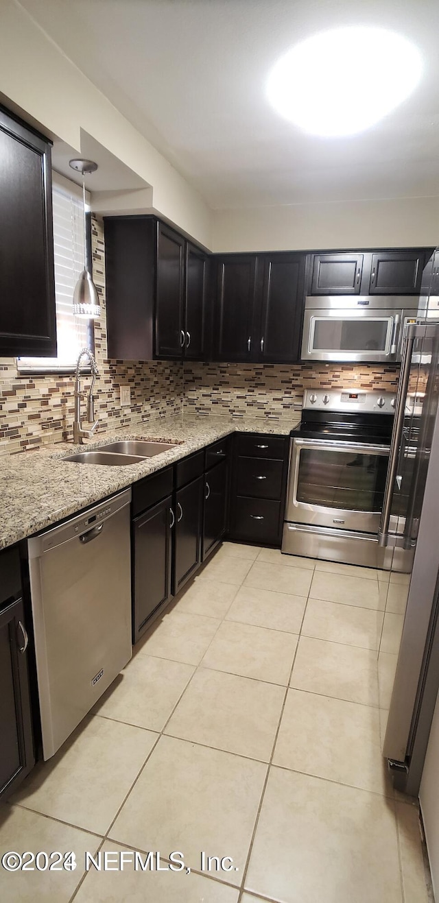 kitchen with stainless steel appliances, light stone counters, sink, light tile patterned floors, and decorative backsplash