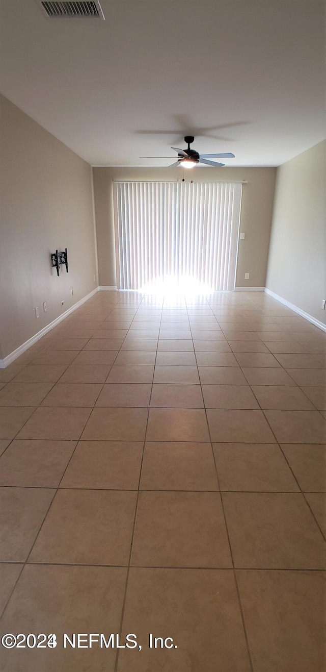 tiled spare room with baseboards, a ceiling fan, and a wealth of natural light