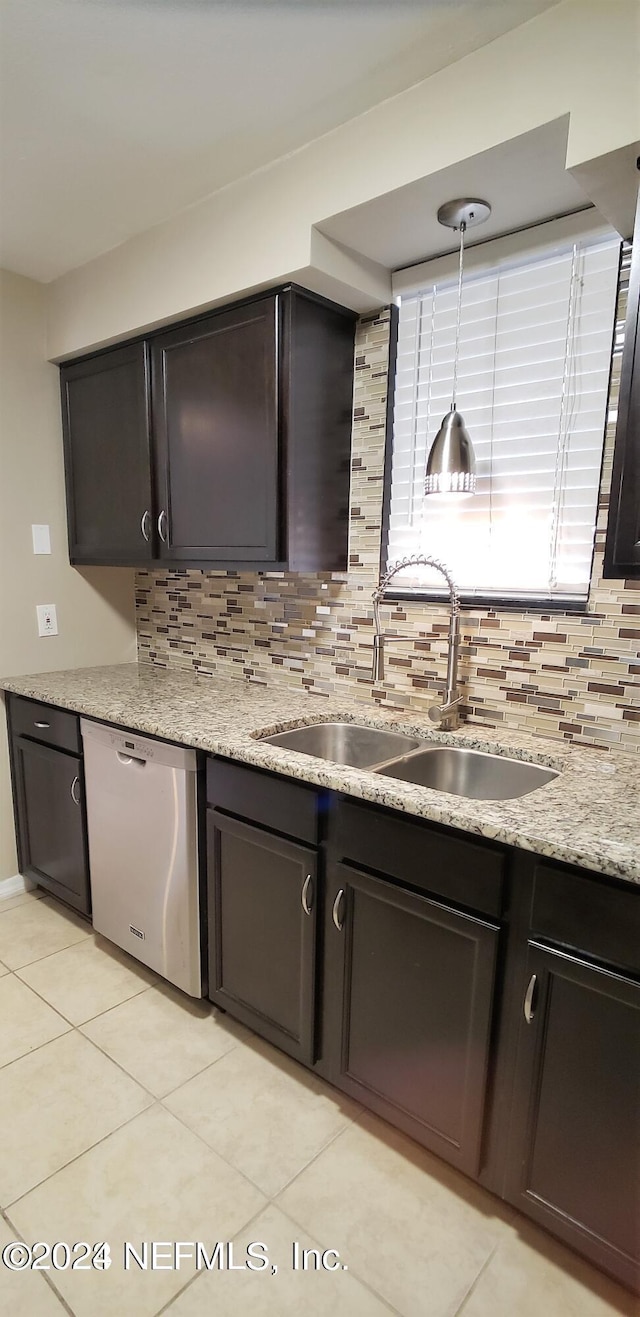 kitchen with dishwasher, light stone counters, backsplash, a sink, and light tile patterned flooring