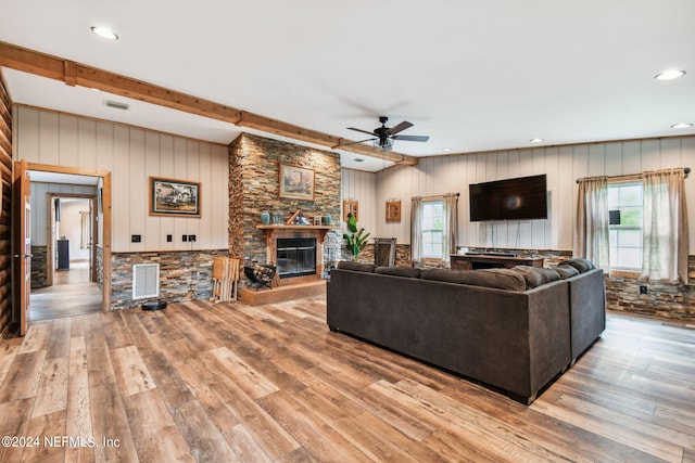 living room with a stone fireplace, light hardwood / wood-style flooring, and a wealth of natural light