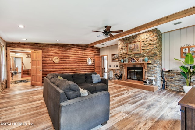 living room featuring vaulted ceiling with beams, a stone fireplace, light hardwood / wood-style flooring, and ceiling fan