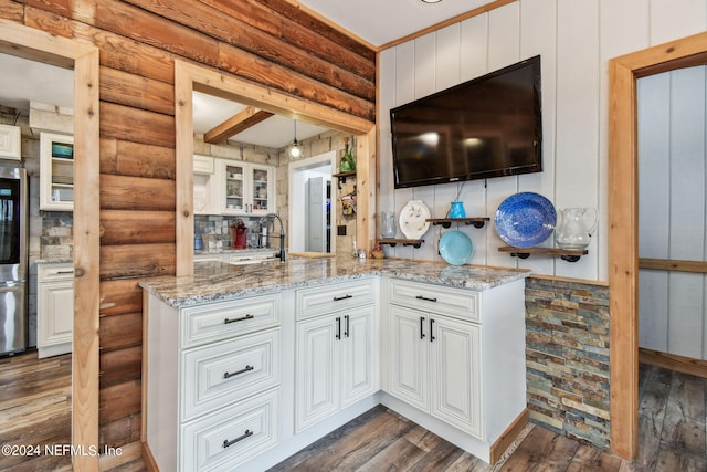 kitchen featuring rustic walls, dark hardwood / wood-style flooring, white cabinets, and light stone counters