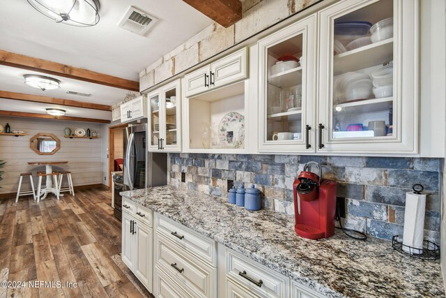 kitchen featuring tasteful backsplash, beam ceiling, and light stone countertops