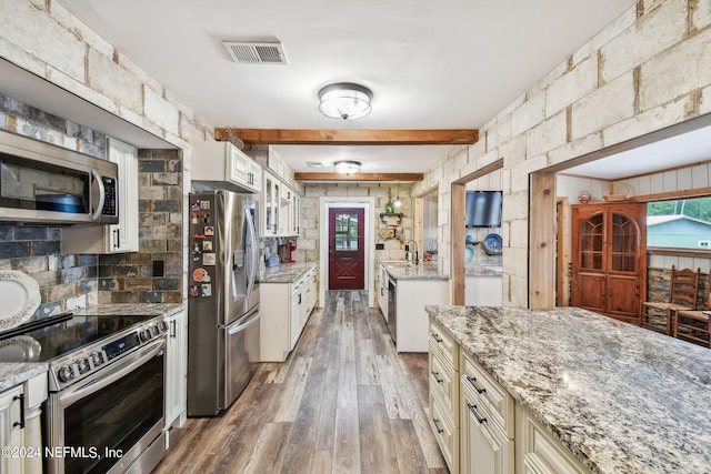 kitchen featuring sink, hardwood / wood-style flooring, appliances with stainless steel finishes, light stone counters, and cream cabinetry