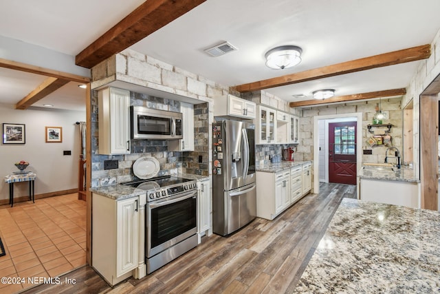 kitchen with light stone counters, white cabinetry, tasteful backsplash, and stainless steel appliances