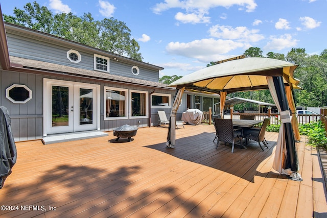 wooden deck featuring a gazebo, grilling area, a fire pit, and french doors