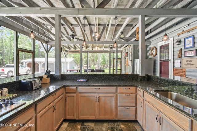 kitchen with ceiling fan, decorative light fixtures, sink, and dark stone countertops