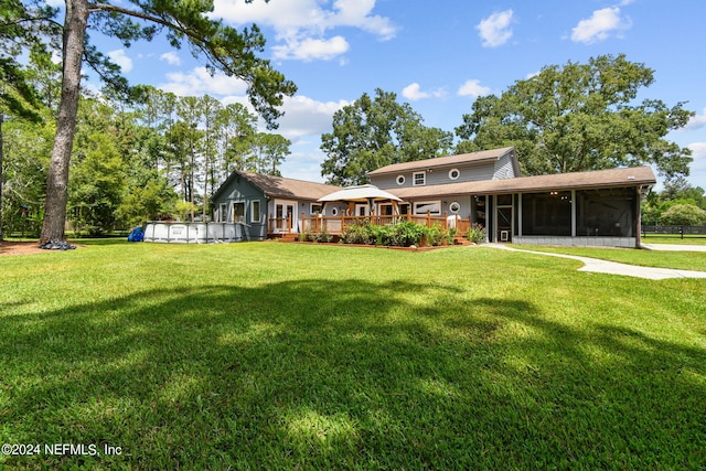 rear view of property featuring a pool side deck, a yard, and a sunroom