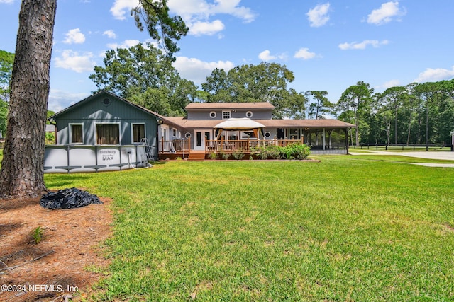 back of house featuring a gazebo, a sunroom, a deck, and a lawn