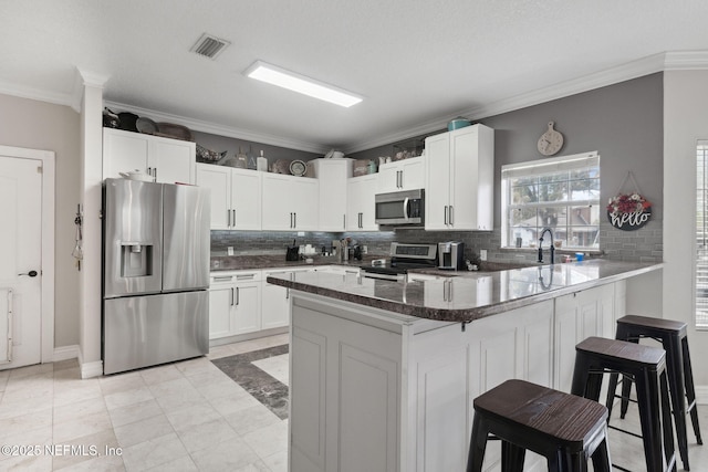 kitchen with a kitchen bar, kitchen peninsula, white cabinetry, and stainless steel appliances