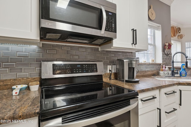 kitchen featuring appliances with stainless steel finishes, tasteful backsplash, sink, dark stone countertops, and white cabinets