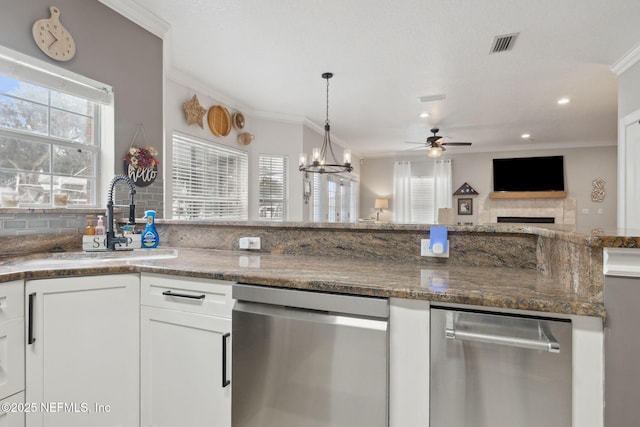 kitchen featuring stainless steel dishwasher, ceiling fan with notable chandelier, white cabinetry, and sink