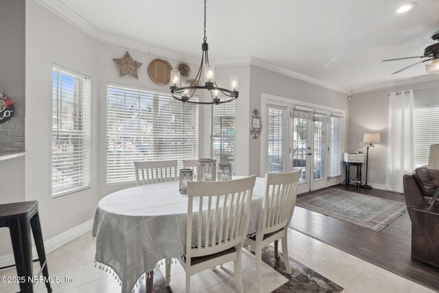 tiled dining room featuring ceiling fan with notable chandelier, crown molding, and french doors