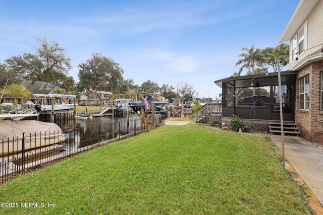 view of yard with a boat dock, a water view, and a sunroom