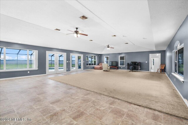 unfurnished living room featuring ceiling fan, french doors, light tile patterned flooring, and vaulted ceiling