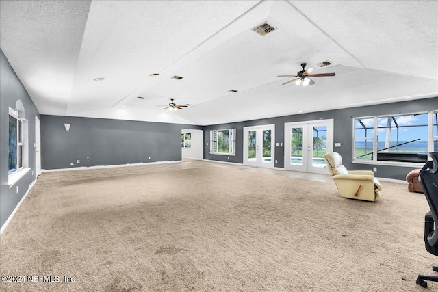 unfurnished living room featuring french doors, a textured ceiling, ceiling fan, vaulted ceiling, and carpet flooring