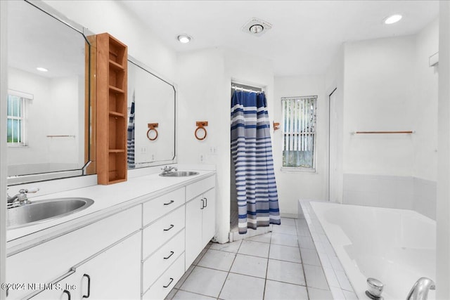 bathroom with dual vanity, a relaxing tiled tub, tile patterned flooring, and a wealth of natural light