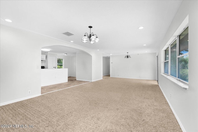 spare room with light carpet and an inviting chandelier