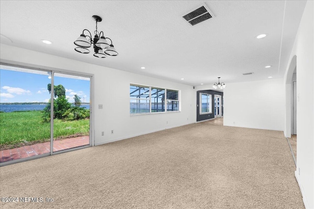 unfurnished living room with a chandelier, light colored carpet, and a textured ceiling