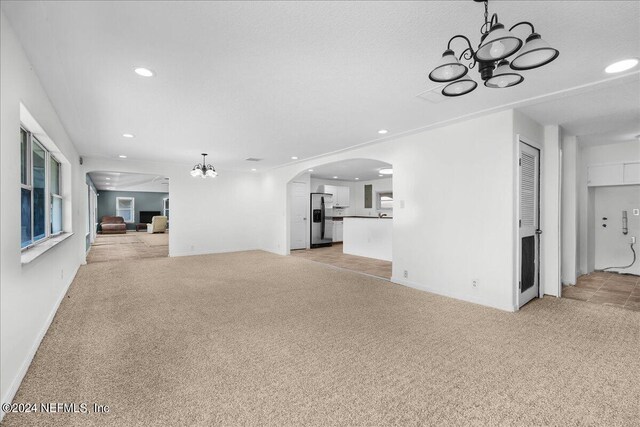 unfurnished living room featuring light carpet and an inviting chandelier