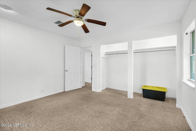 unfurnished bedroom featuring light carpet, multiple closets, and ceiling fan