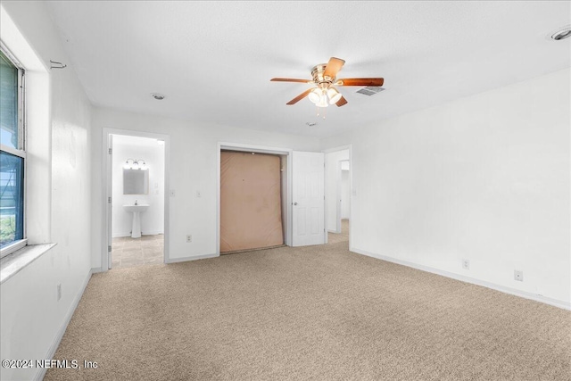 unfurnished bedroom with light carpet, ceiling fan, and connected bathroom