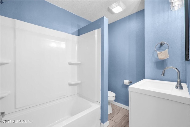 full bathroom featuring a textured ceiling, toilet, shower / washtub combination, vanity, and hardwood / wood-style floors