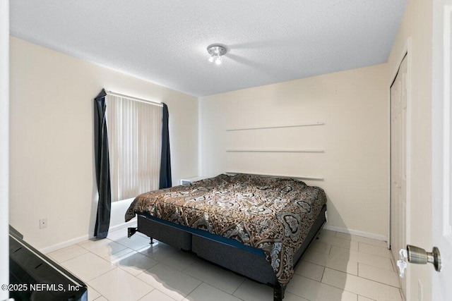 tiled bedroom featuring a textured ceiling and baseboards