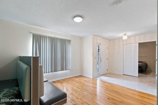 foyer entrance featuring a textured ceiling, baseboards, and wood finished floors