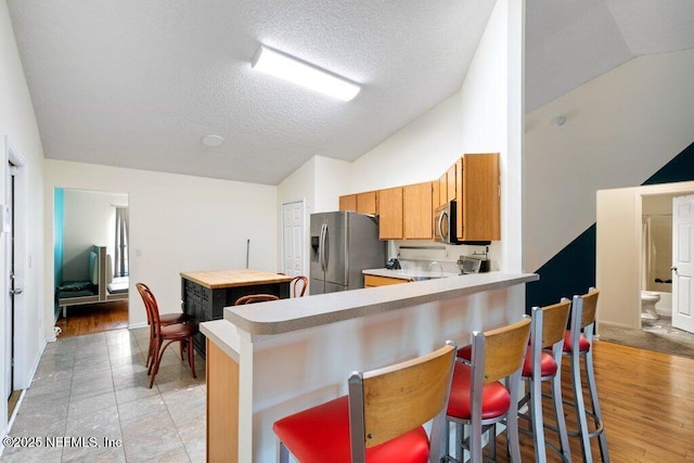 kitchen with lofted ceiling, stainless steel appliances, a peninsula, and light countertops