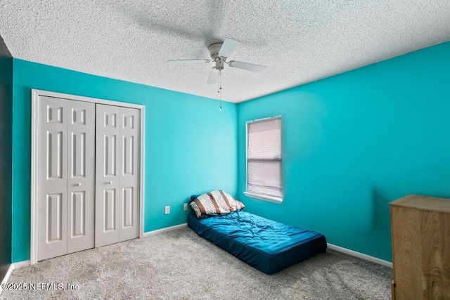 carpeted bedroom with baseboards, a textured ceiling, a ceiling fan, and a closet