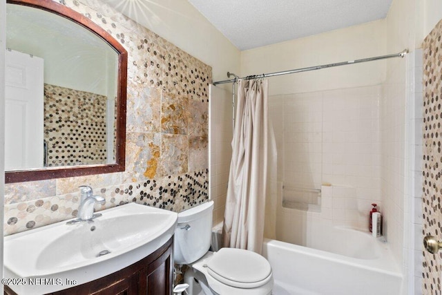 full bath with toilet, shower / bath combo with shower curtain, a textured ceiling, vanity, and tile walls