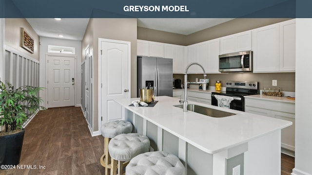 kitchen with an island with sink, stainless steel appliances, dark hardwood / wood-style floors, and white cabinets