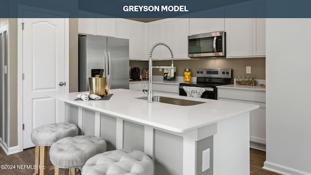 kitchen featuring a center island with sink, white cabinetry, a kitchen bar, and stainless steel appliances