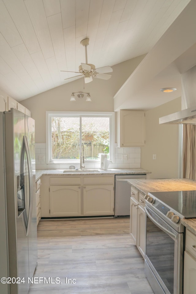 kitchen with decorative backsplash, lofted ceiling, appliances with stainless steel finishes, light countertops, and a sink