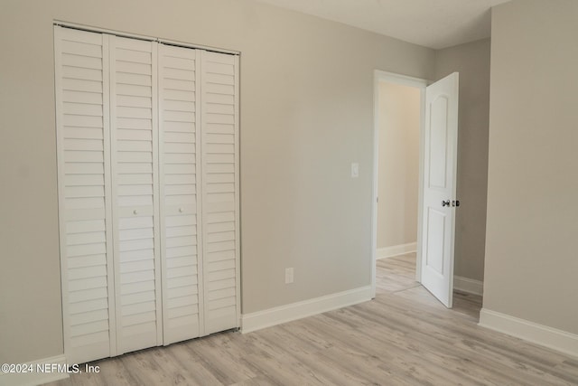 unfurnished bedroom with light wood-style floors, baseboards, and a closet