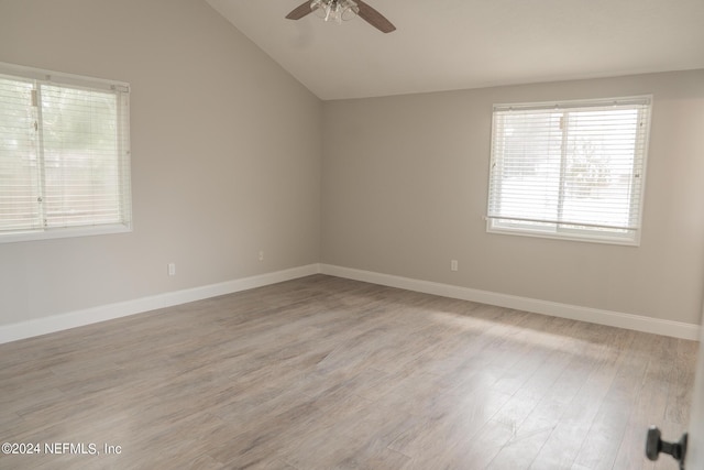 spare room with vaulted ceiling, ceiling fan, light wood-style flooring, and baseboards