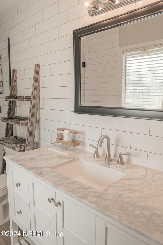 bathroom with toilet, tasteful backsplash, tile walls, and vanity