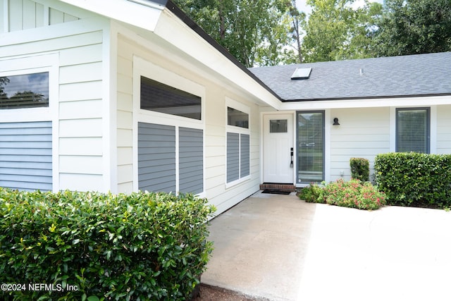 doorway to property with a shingled roof and board and batten siding